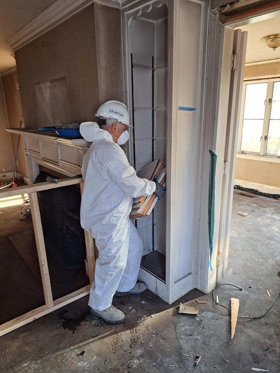 A man in a protective suit is working on a door in a room.