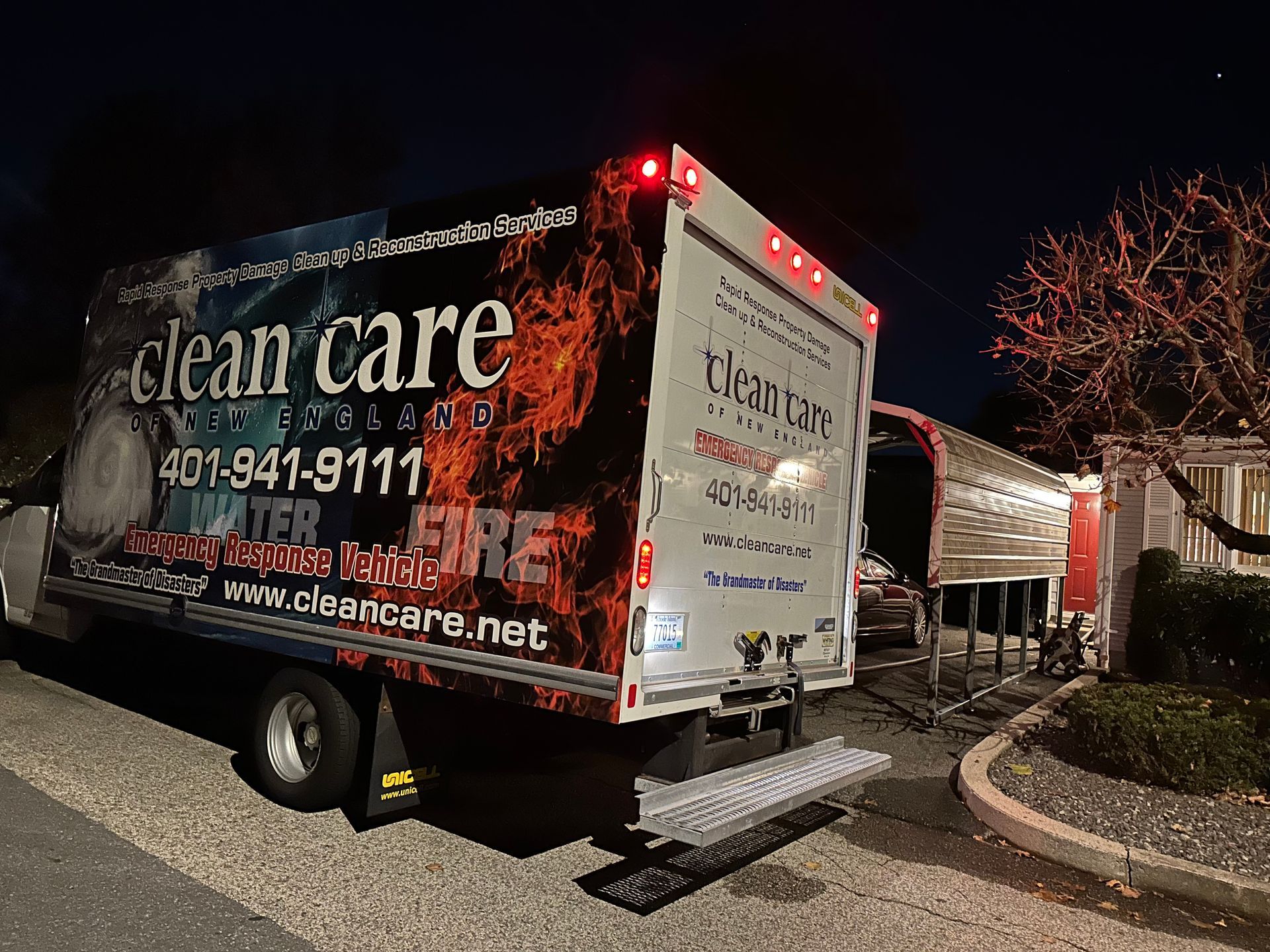 A clean care truck is parked on the side of the road at night.