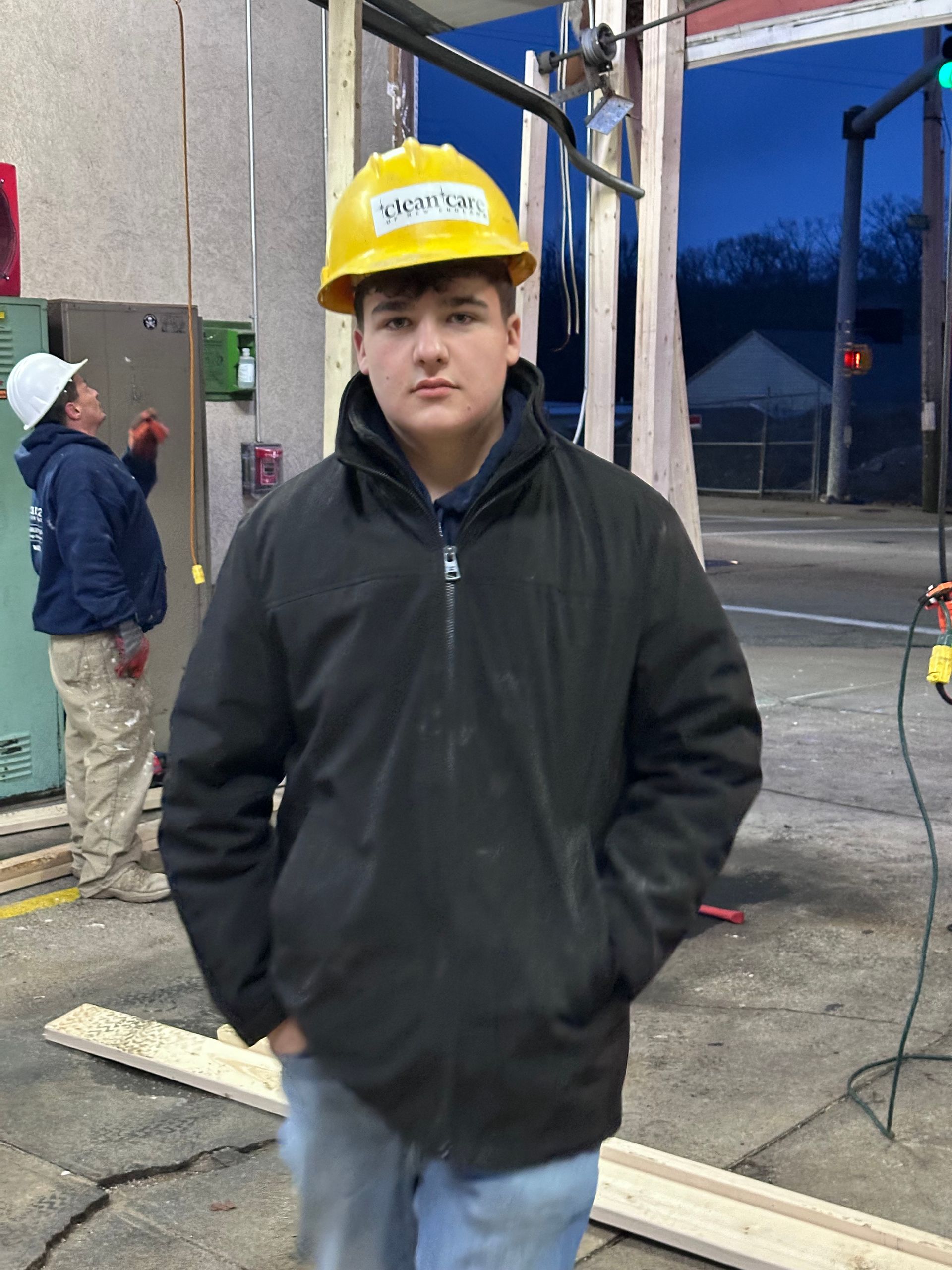 A young man wearing a hard hat and a black jacket