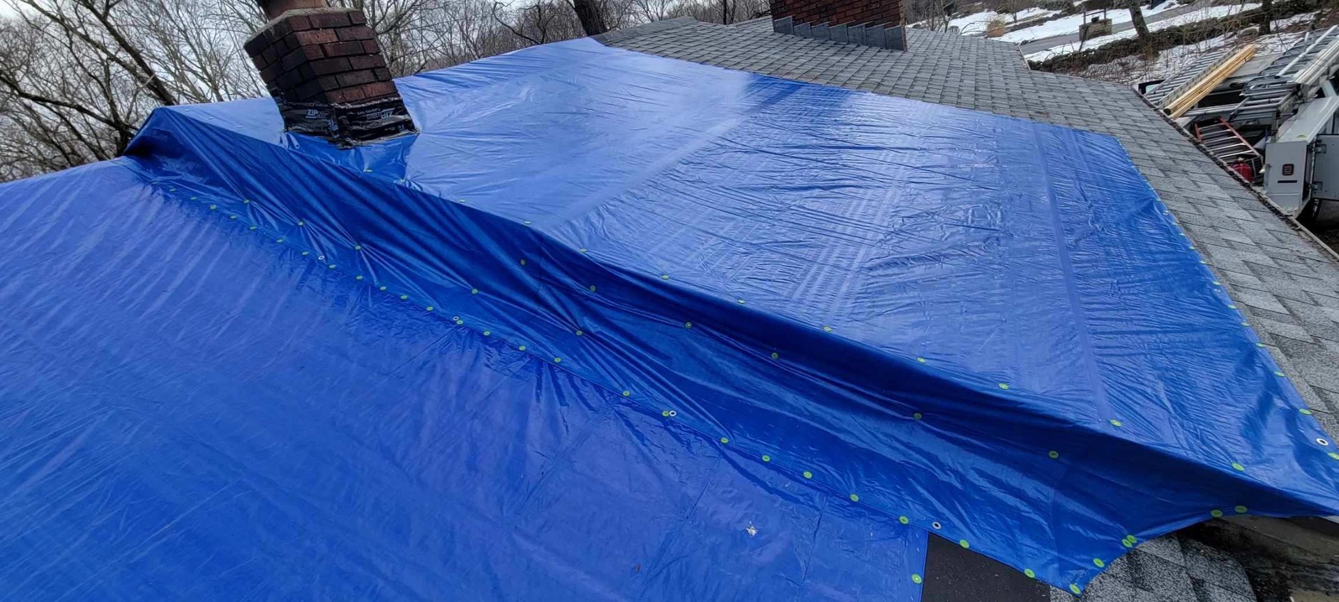 A blue tarp is covering the roof of a house.