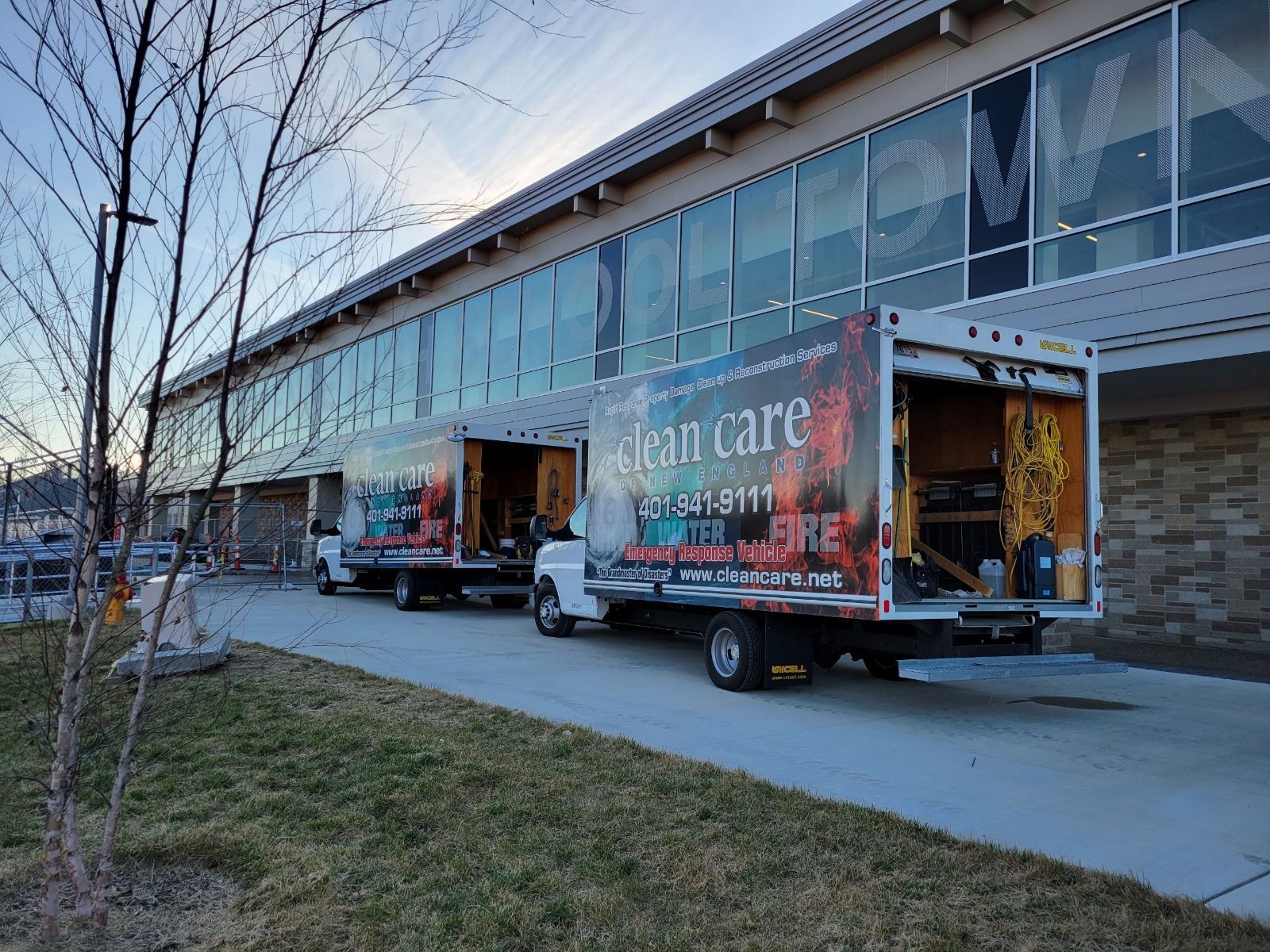 Two trucks are parked in front of a building with their doors open.