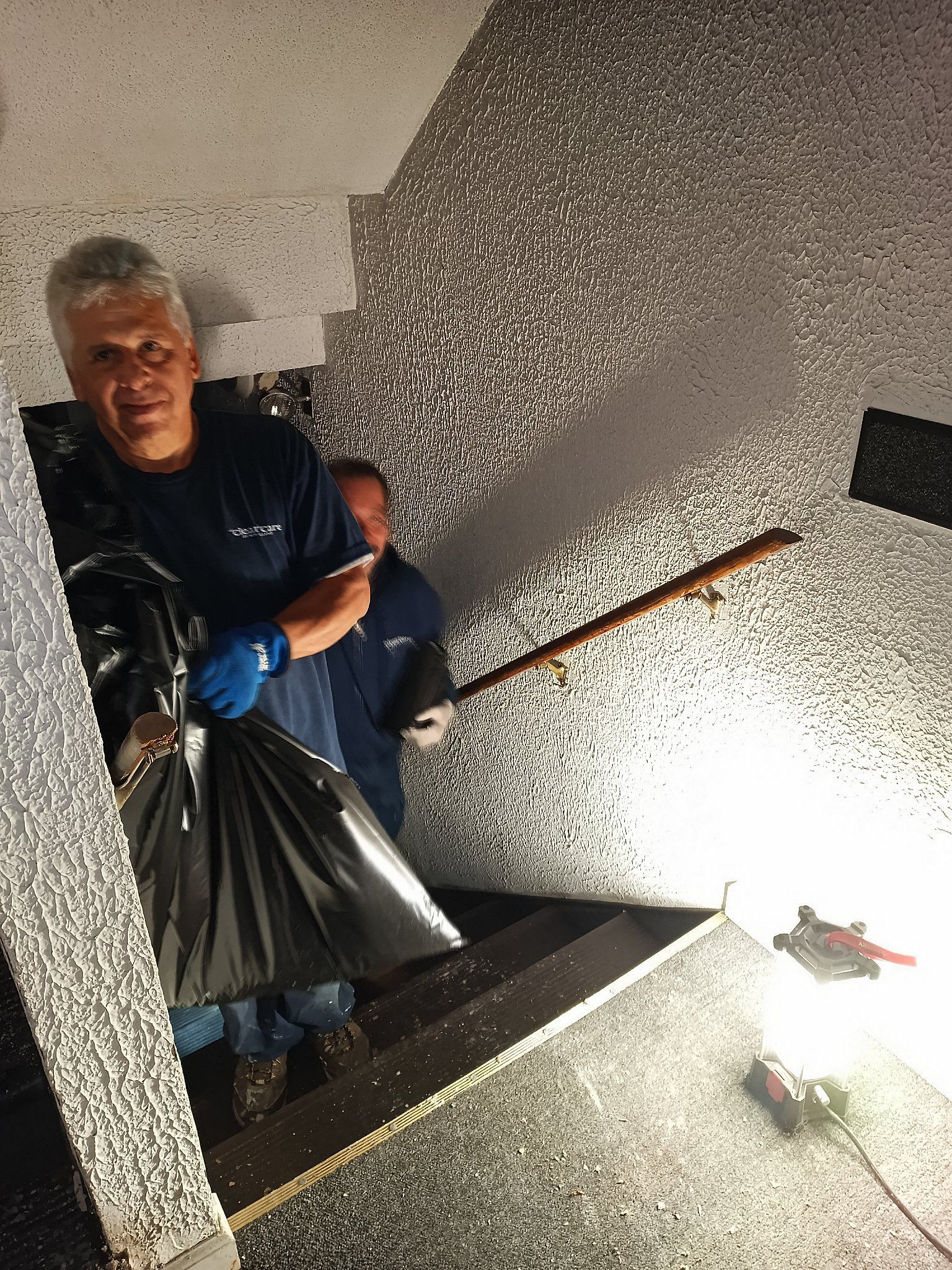 A man is standing on a set of stairs holding a bag of trash.