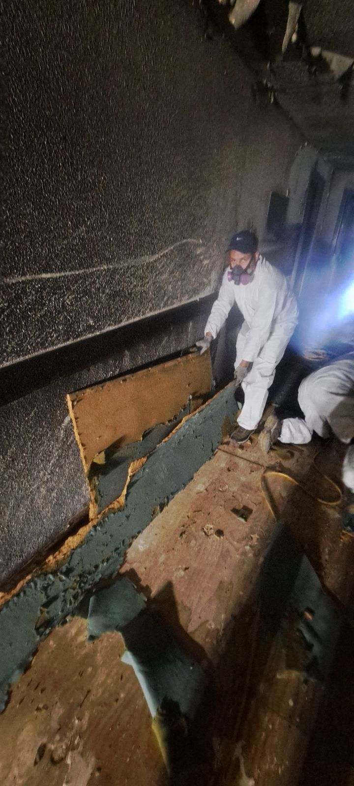A man in a white suit is working on a roof.