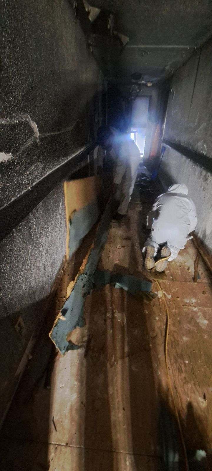 A man is standing in a dark room with a flashlight.