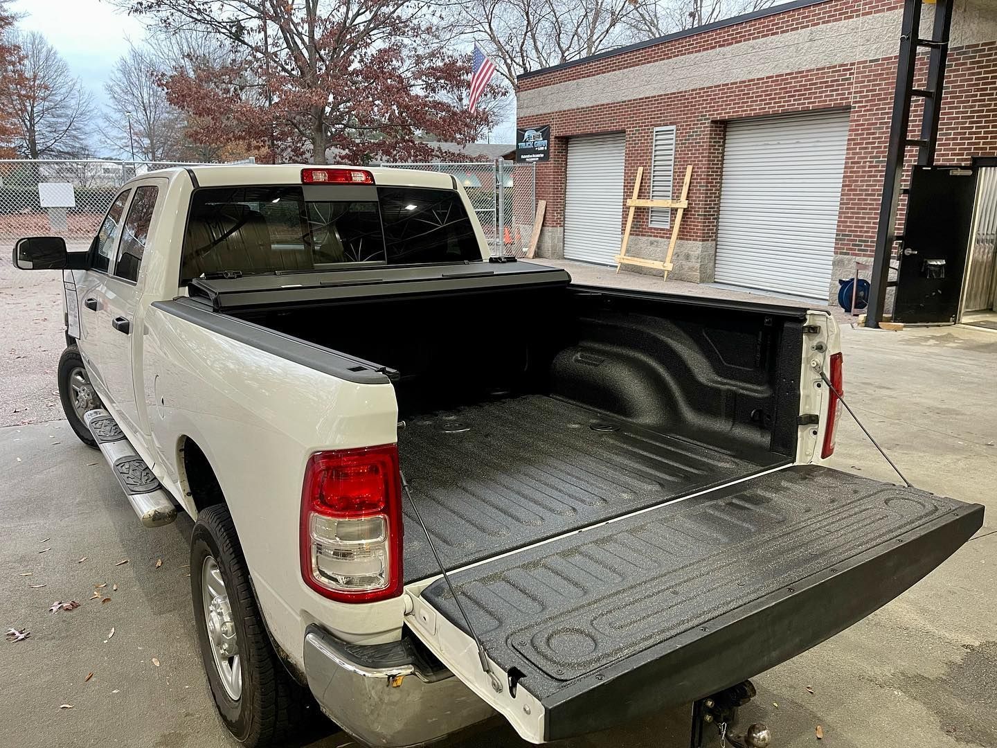 White pickup truck with open bed in front of brick building.