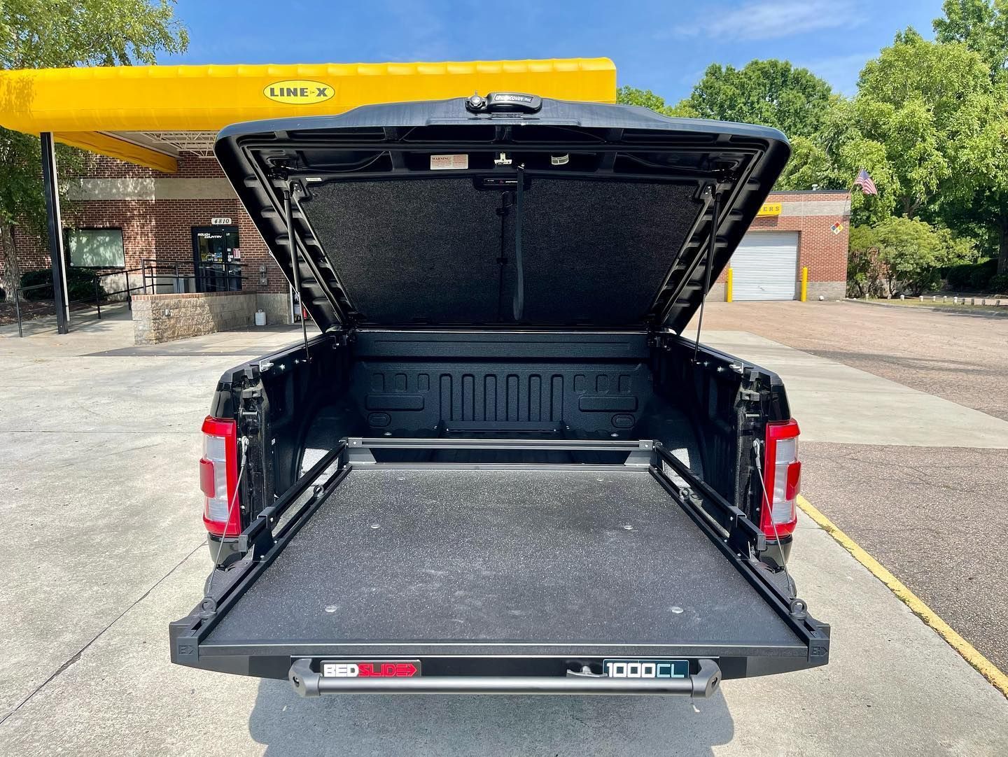 Black truck bed with open tonneau cover. Truck bed is extended.
