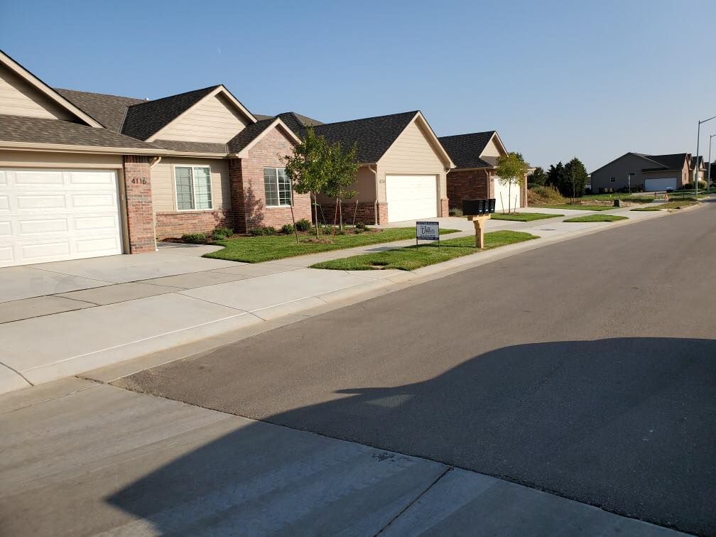 Row of attached houses with brick facades and white garages on a sunny street.