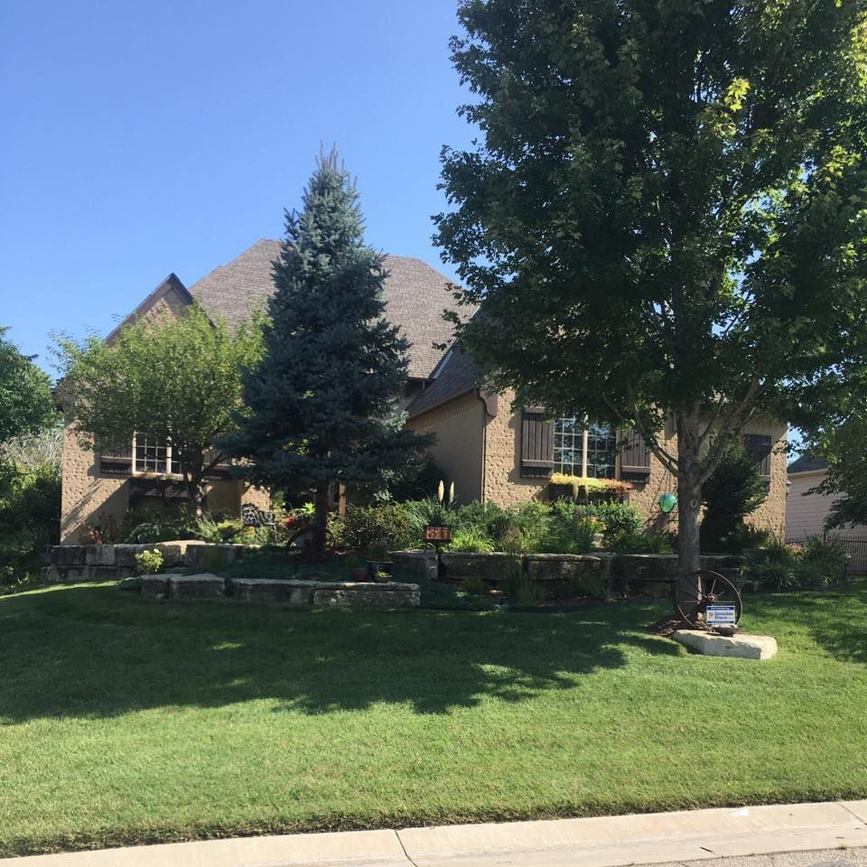House with brick exterior, landscaping and grass. Blue sky.
