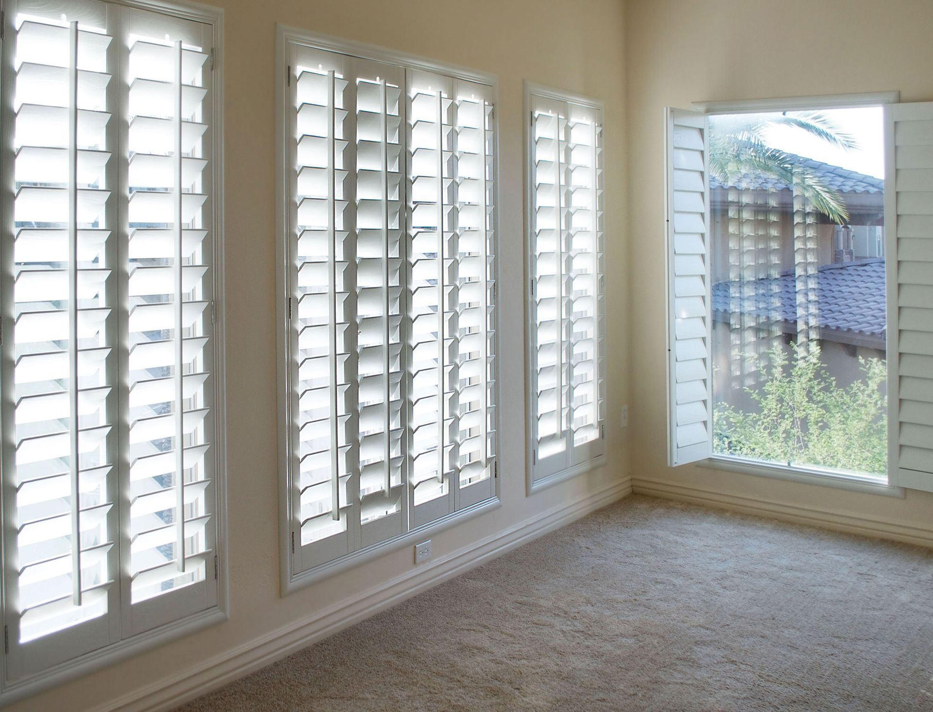 An empty room with white shutters on the windows