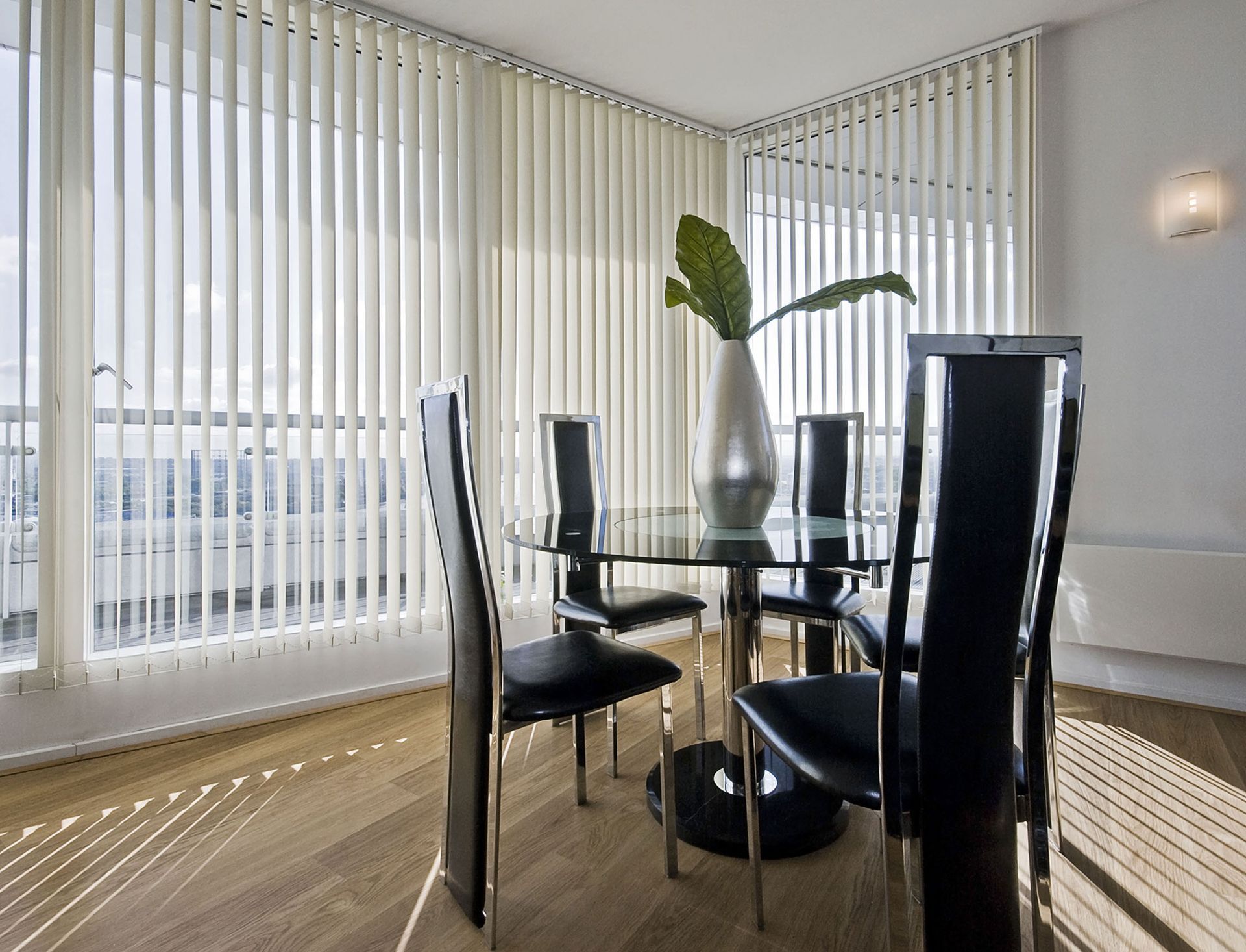 A dining room with a table and chairs and vertical blinds