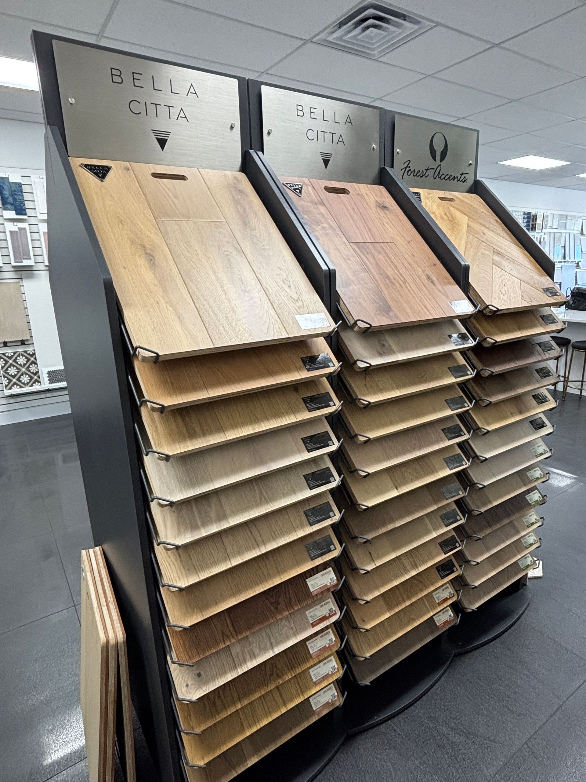 Floorboard samples in a display stand at a showroom, featuring various wood tones and textures.