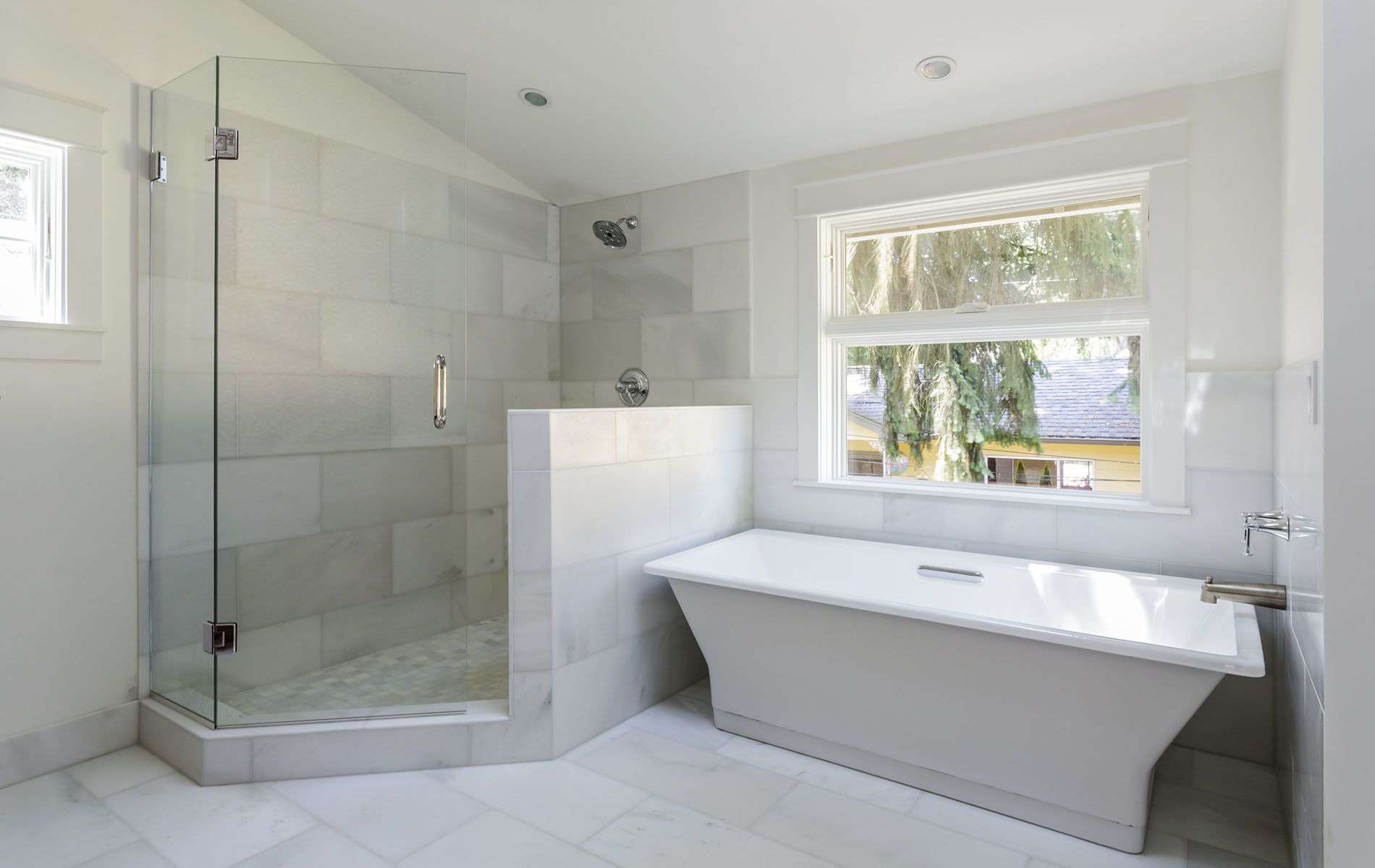 A bathroom with a tub , shower , and window.