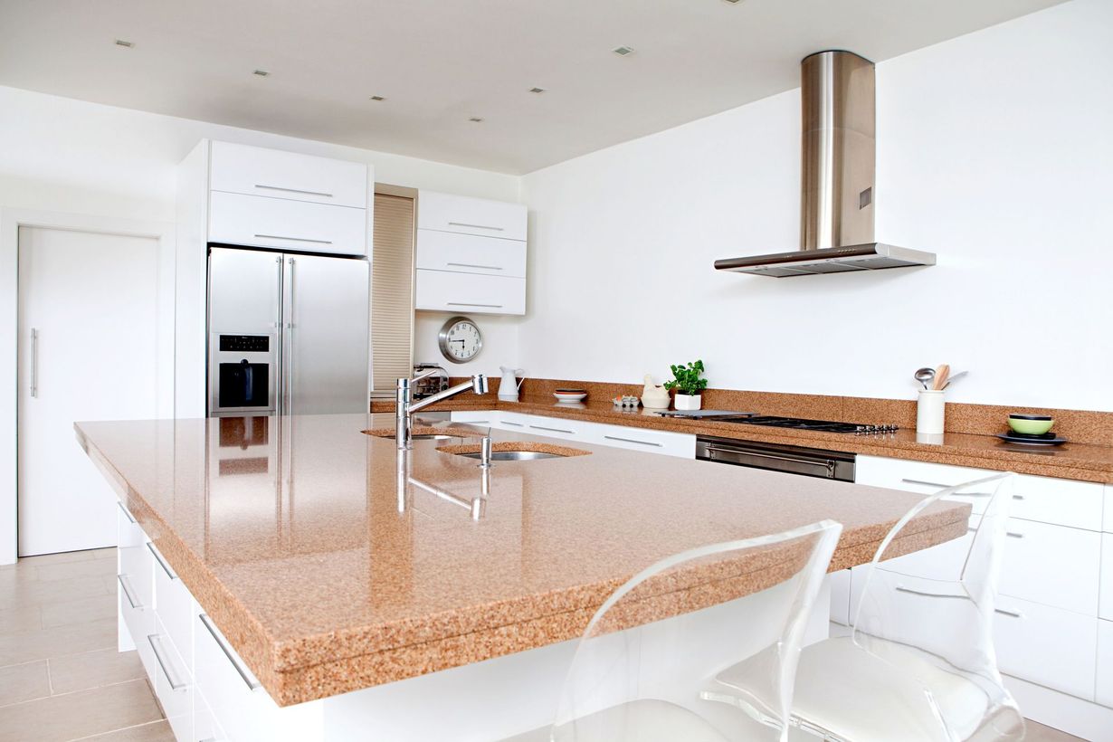 Bright modern kitchen with white cabinets, stainless fridge, and a large granite island
