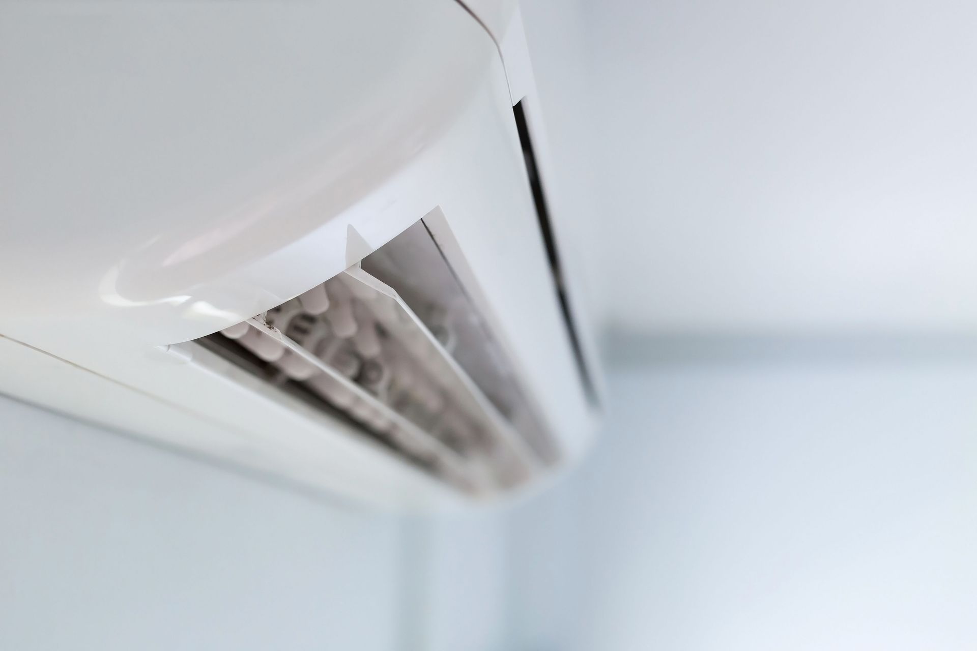 White air conditioner mounted on a white ceiling.