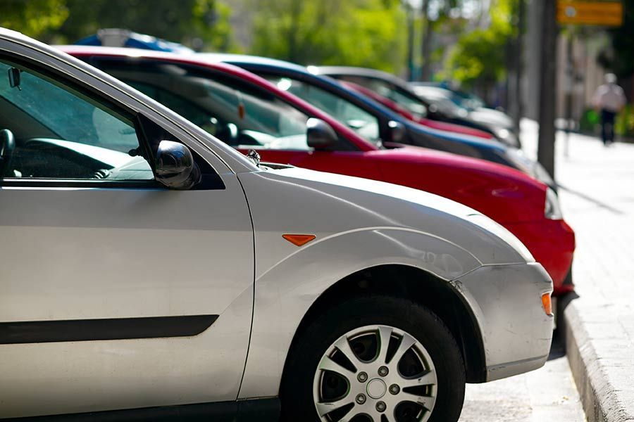 Cars parked along a street, with a silver car in the foreground.