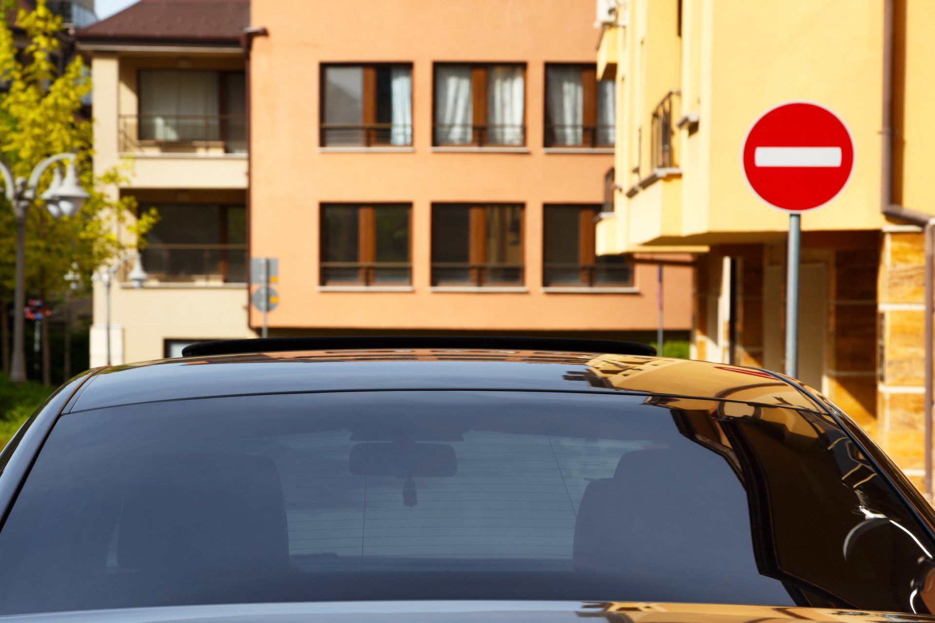 Black car parked near buildings and a red and white 