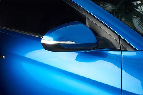 Blue car side mirror, sleek design with integrated turn signal.