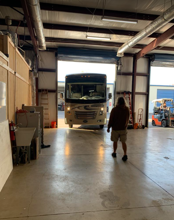 a man stands in front of a ford rv in a garage