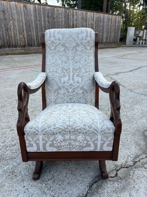 Antique upholstered armchair with floral fabric and dark wooden frame, outdoors on a concrete driveway