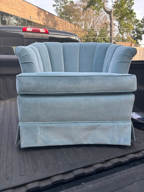 Blue upholstered loveseat on a black truck bed, photographed outdoors.
