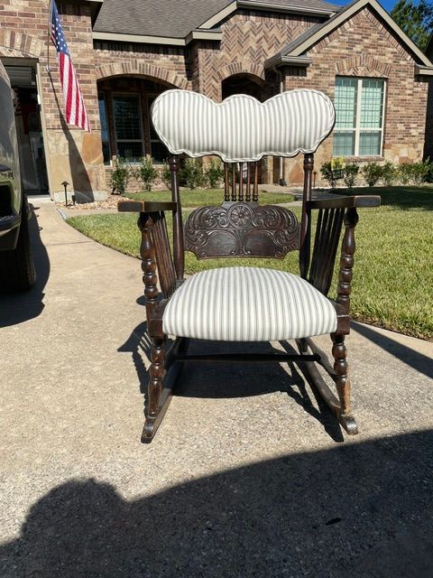 White striped upholstered chair on a driveway in front of a brick house.