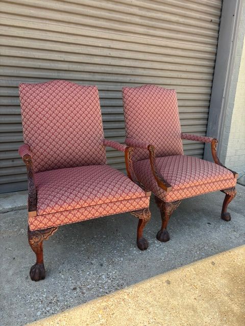 Two patterned upholstered armchairs with wooden arms and legs in front of a metal roll-up door