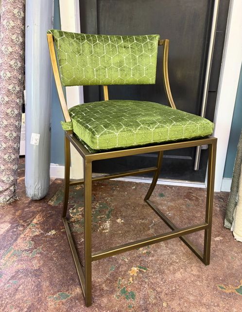 Green upholstered bar stool with dark metal frame in a doorway