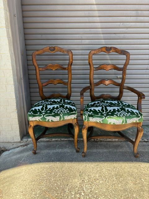 Two wooden chairs with green floral cushions in front of a closed metal roll-up door