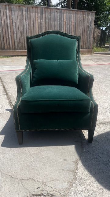 Emerald green upholstered armchair with nailhead trim, placed outside.