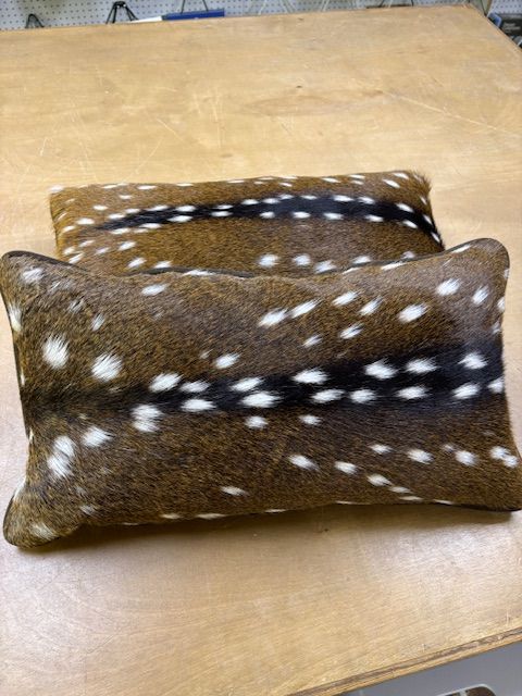 Two rectangular throw pillows with brown and white spotted pattern, resembling deer hide.