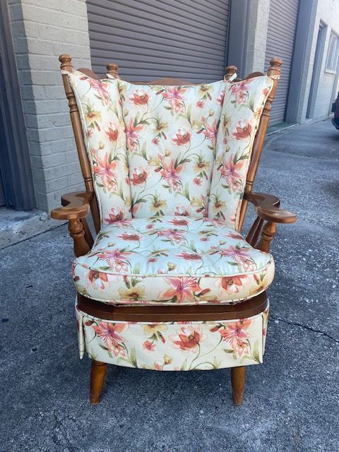 Floral patterned armchair with wooden frame, outdoors.