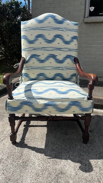 Wooden armchair with blue and white patterned upholstery; outdoors.