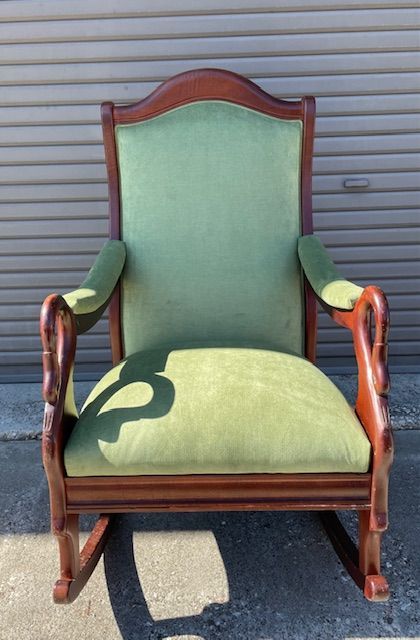 Antique green velvet rocking chair with brown wood frame.