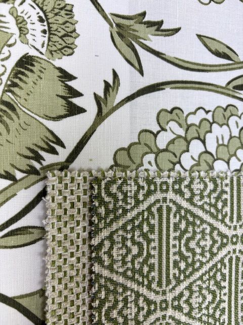 Close-up of white fabric with green floral print, alongside textured green and white patterned fabric samples.