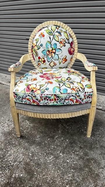 Floral-patterned armchair with tan frame, set against a gray background.