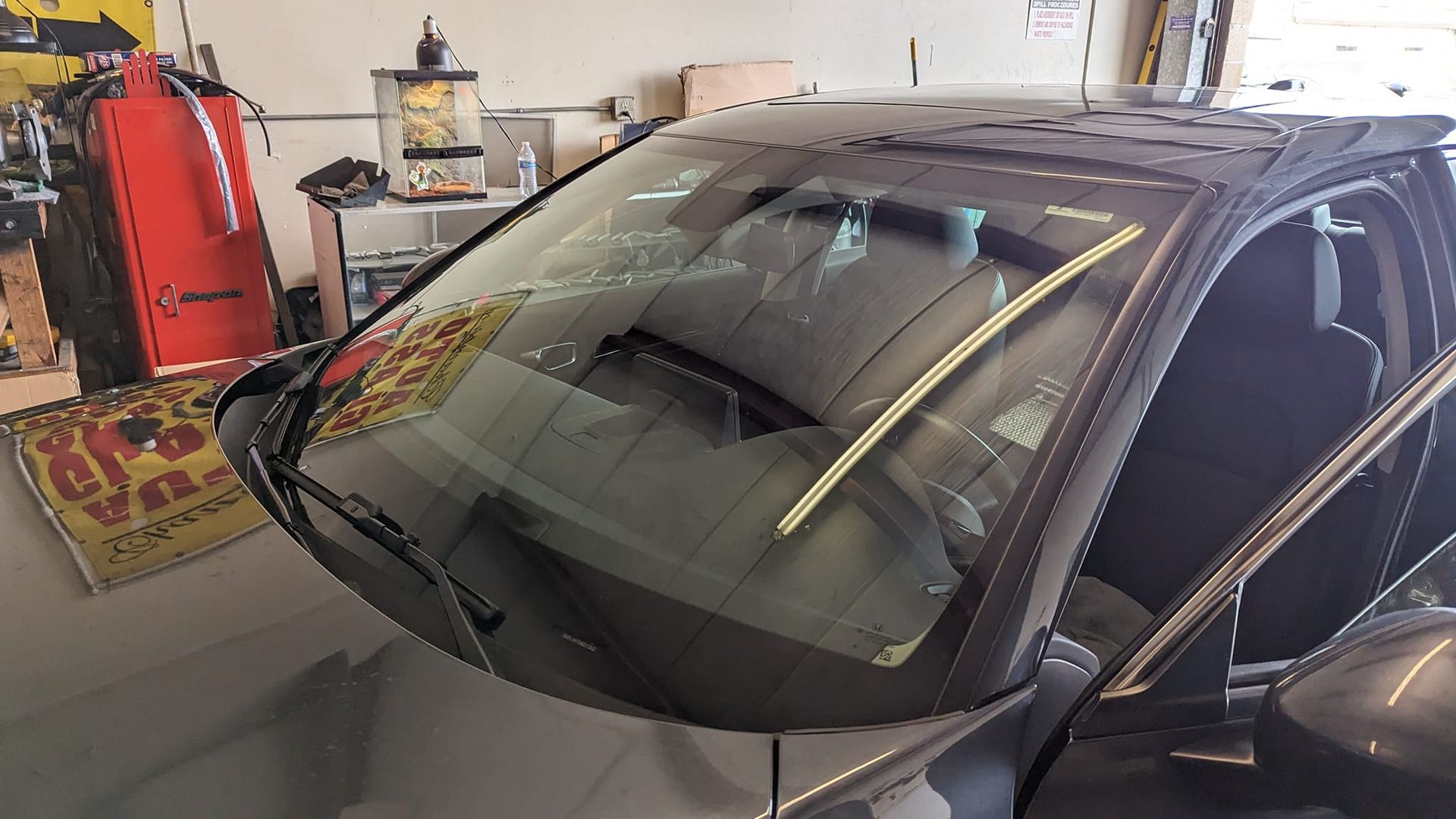 Car with damaged windshield in a garage.