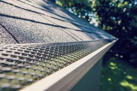 A close-up of a gutter with a mesh on it.