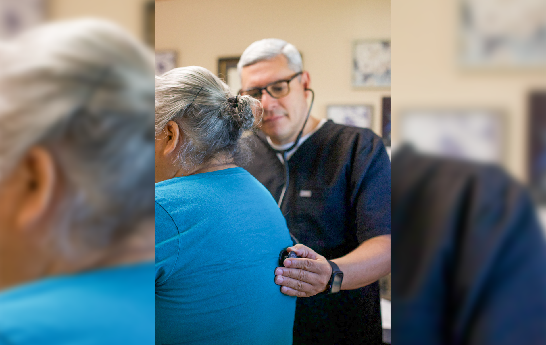 Doctor listening to patient's back with stethoscope in a medical office.