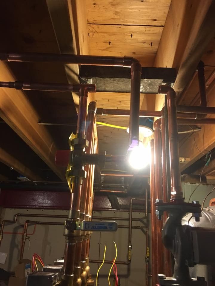Copper pipes and valves against wooden beams, lit from below.