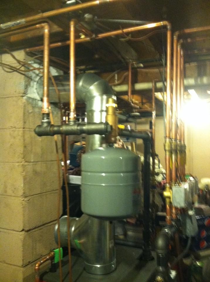 Copper pipes and boiler system in a basement setting.
