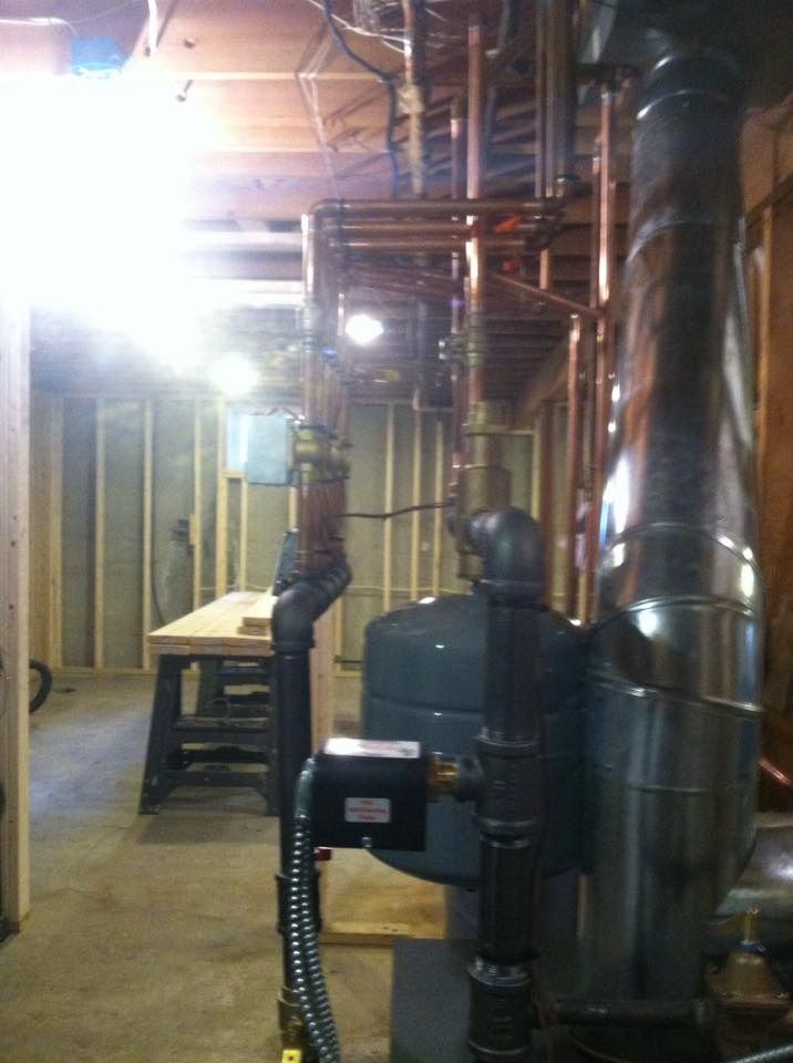 Copper pipes and insulated ducts in a basement; construction in progress.