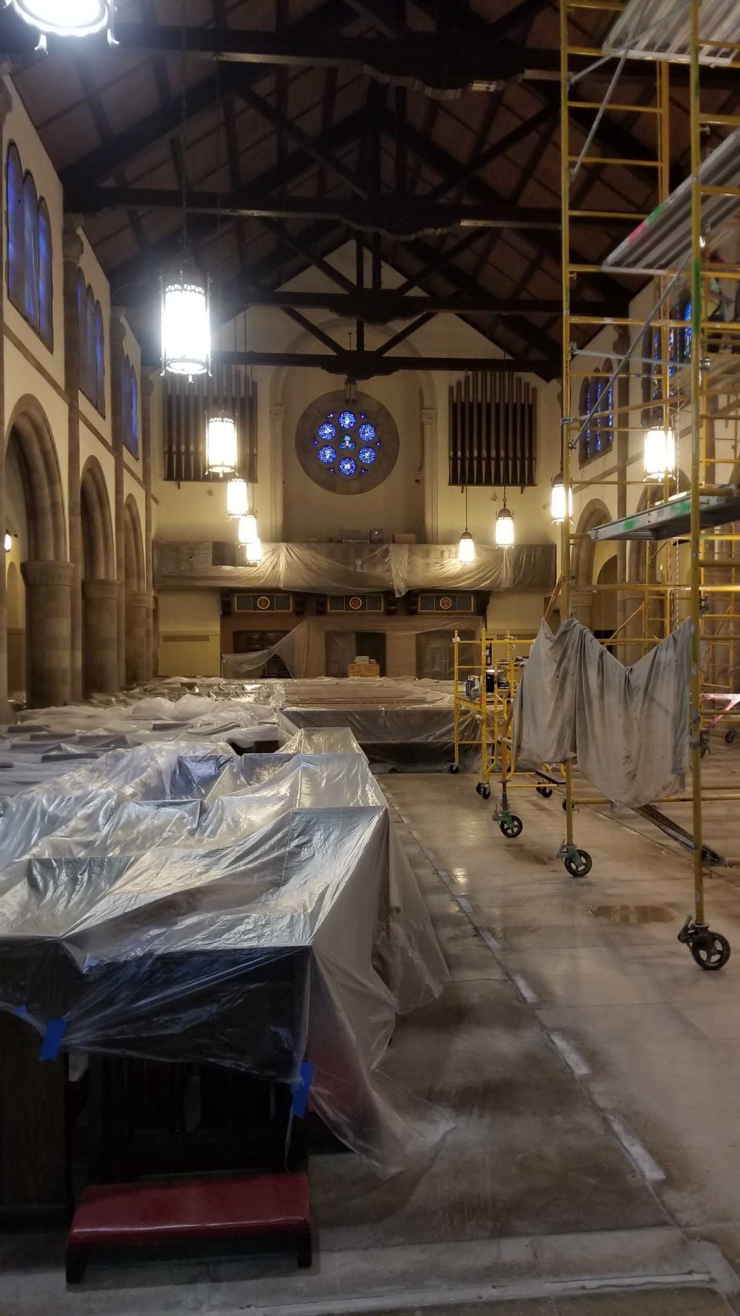 A large room with scaffolding and plastic covering the floor.