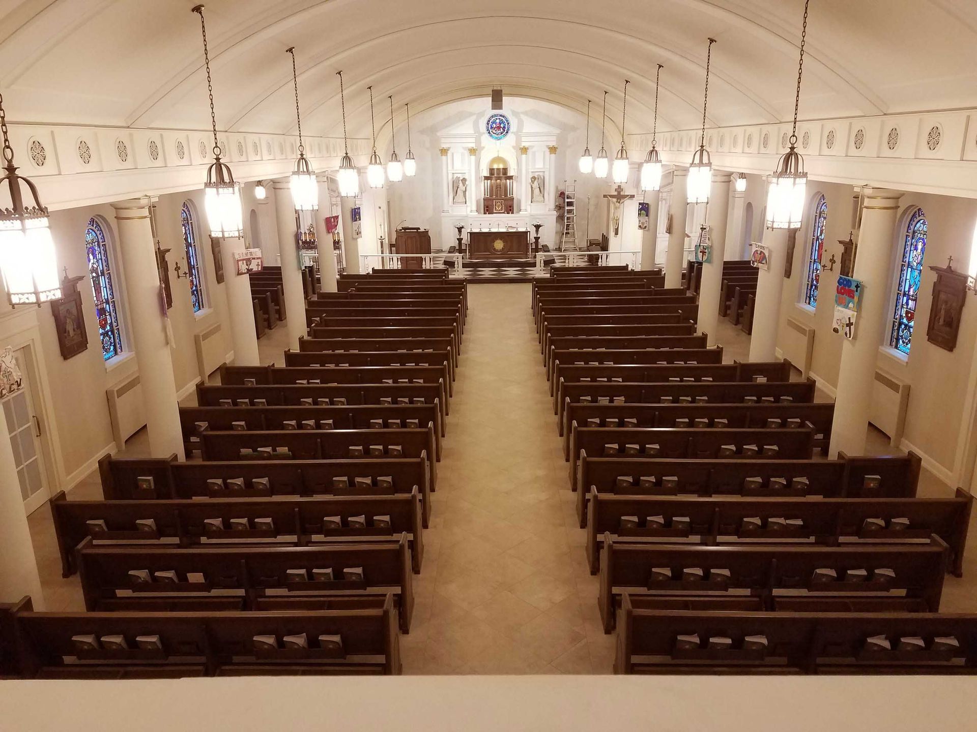 The inside of a church with rows of benches and stained glass windows