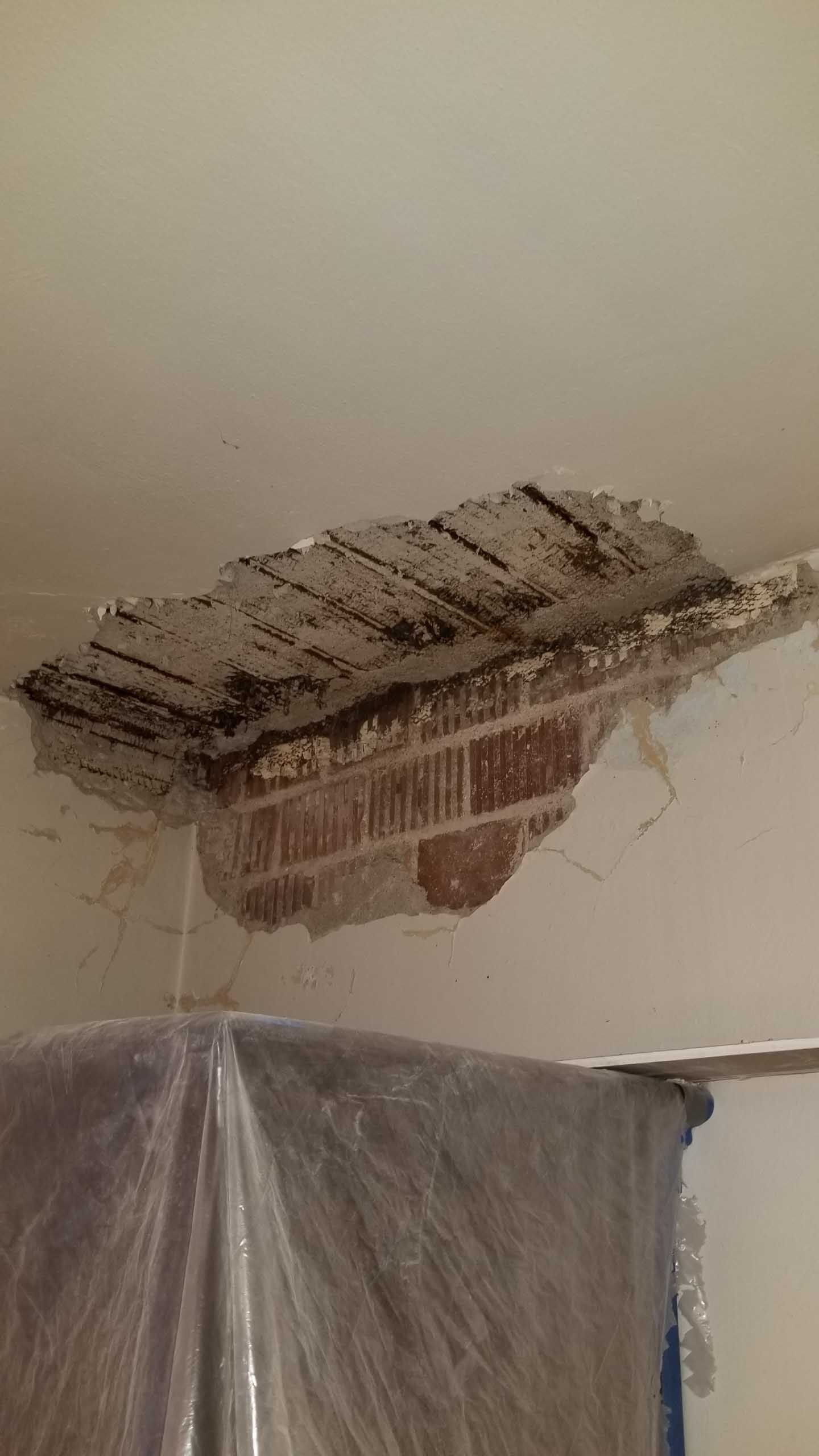 A piece of brick is missing from the ceiling of a room.