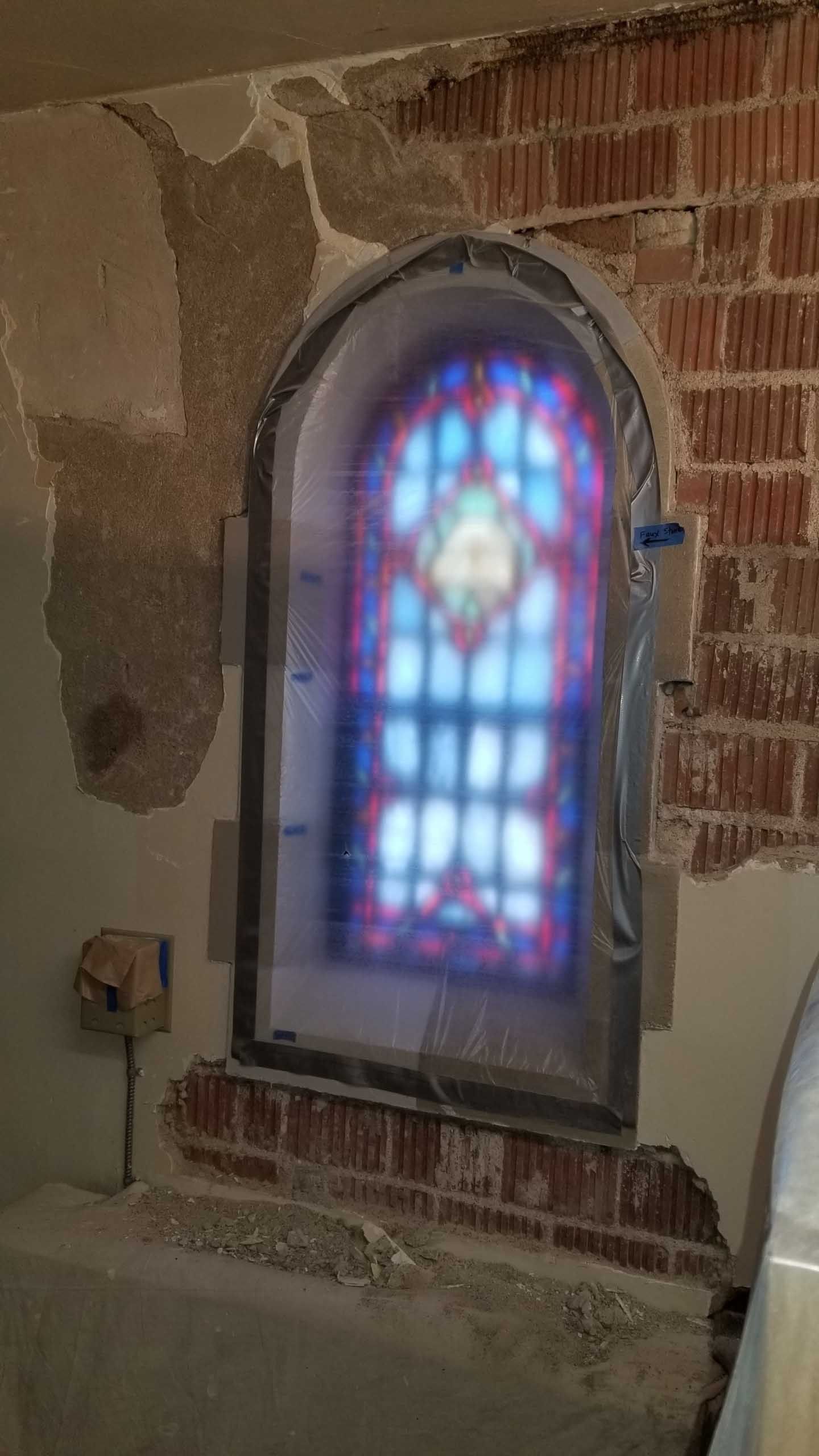 A brick wall with a stained glass window in it.