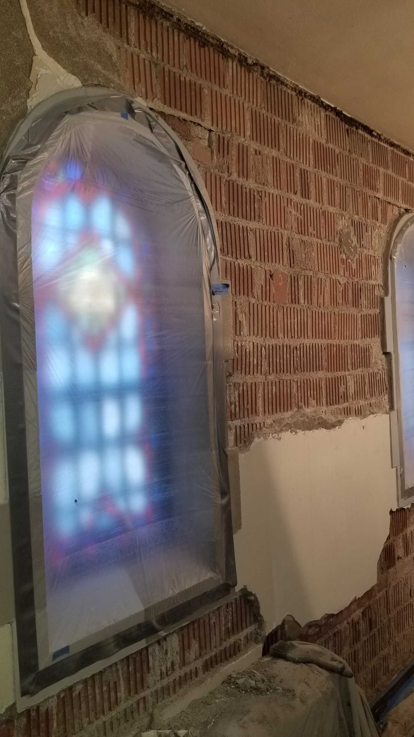 A brick wall with a stained glass window in it.