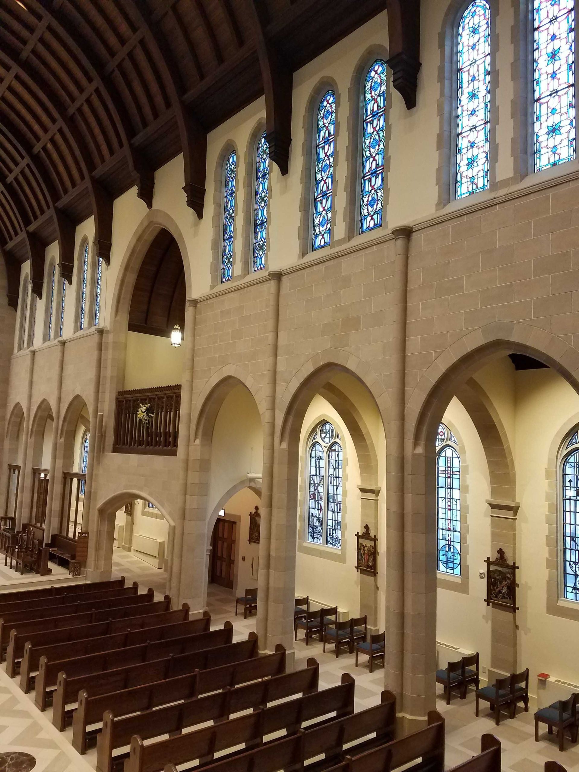 A church with rows of wooden benches and stained glass windows