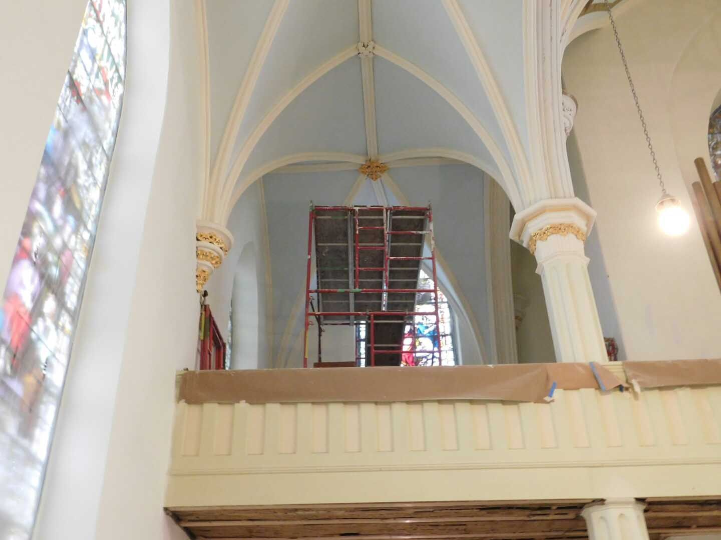 The inside of a church with a balcony and scaffolding.