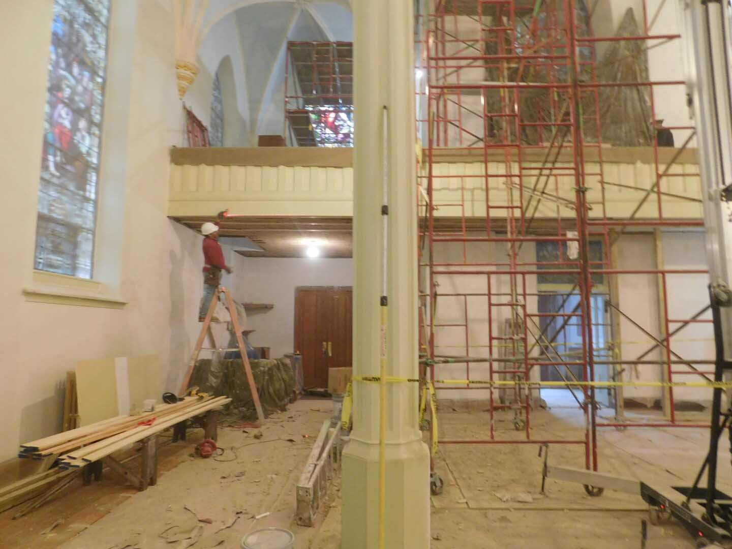 A man is standing on a ladder in a church under construction.