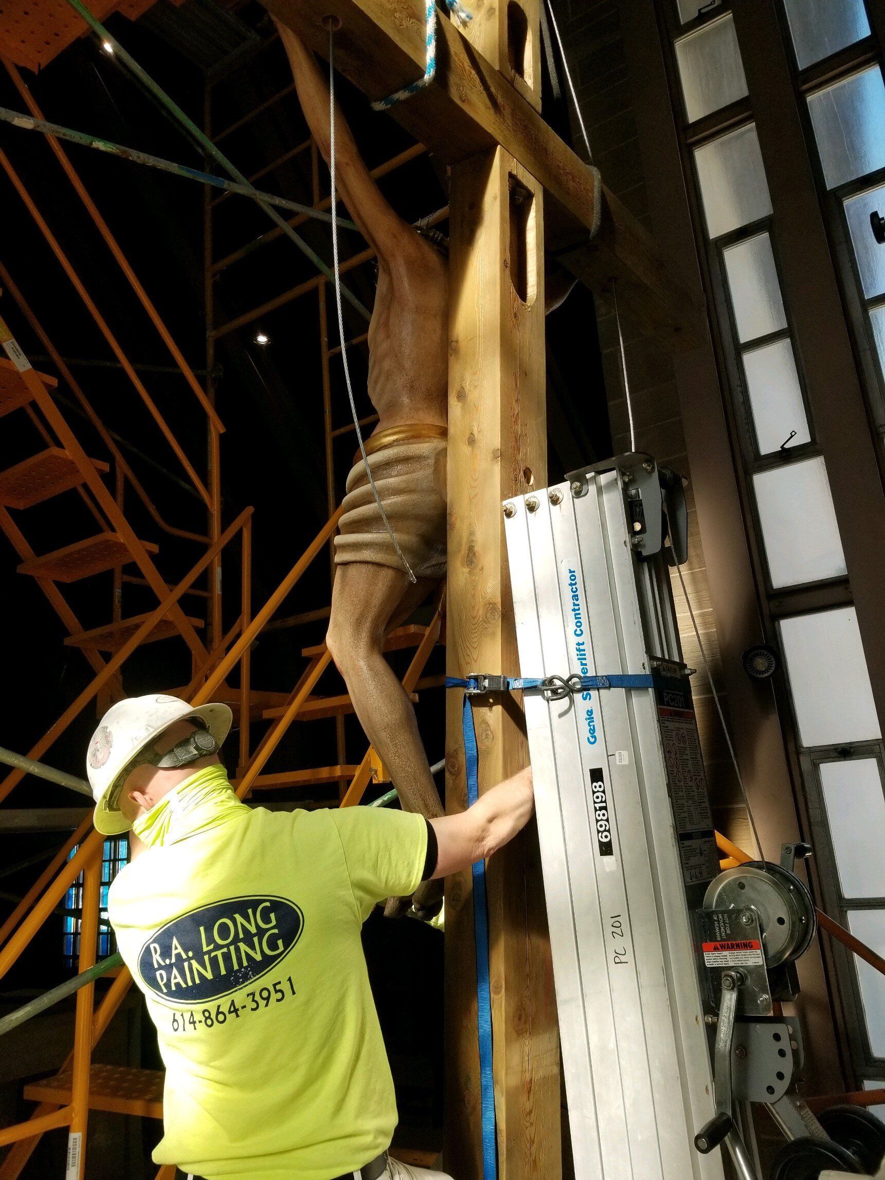 A man wearing a yellow shirt that says la long santiago is working on a cross